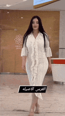 a woman in a white dress walking in front of a grozny mall sign