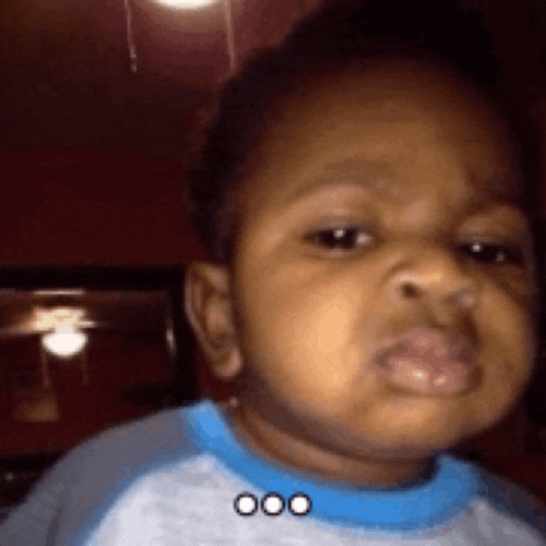a baby is wearing a blue shirt and making a funny face