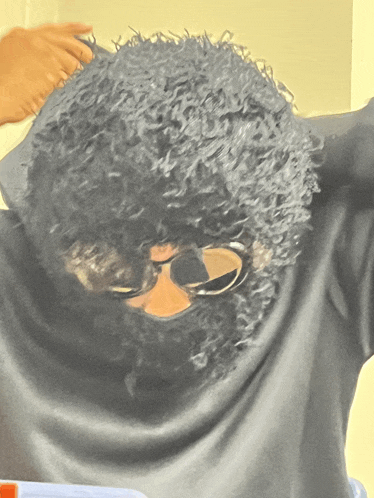 a person with curly hair is wearing sunglasses