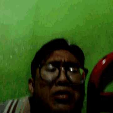 a man wearing glasses making a funny face in front of a green wall