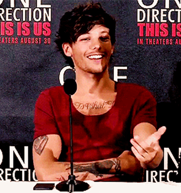 a man with a tattoo on his chest is smiling in front of a sign that says direct this in theaters august 30