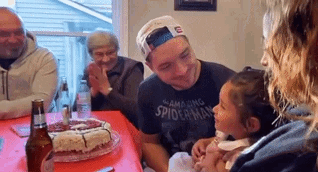 a man wearing a spider man shirt holds a little girl