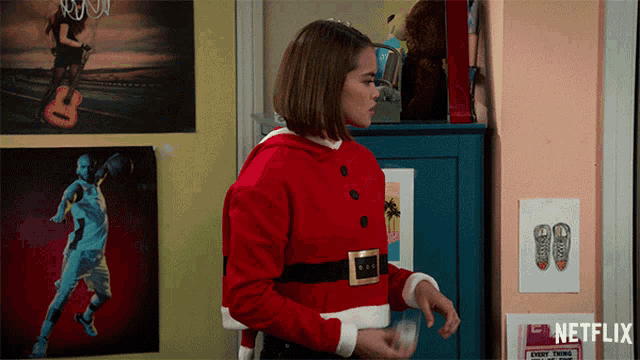 a girl in a santa suit is standing in front of a netflix sign