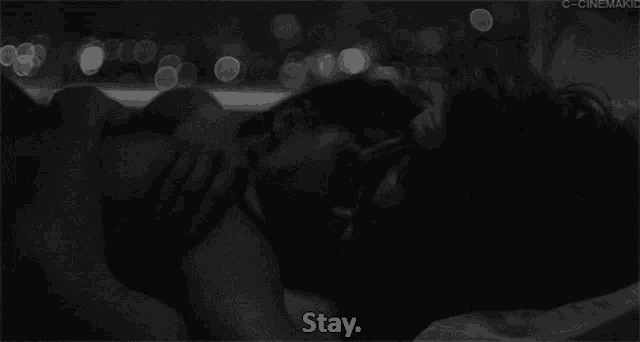 a black and white photo of a man and woman kissing with the words " stay " above them