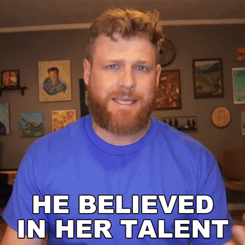 a man with a beard is wearing a blue shirt that says " he believed in her talent "