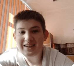 a young boy is smiling in front of a window with blinds