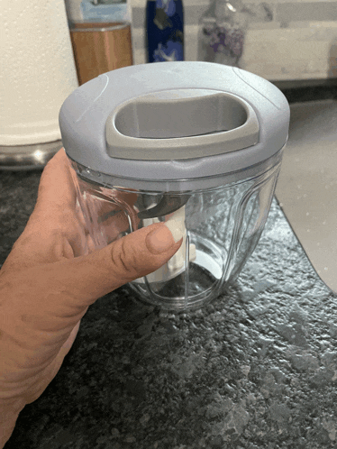 a person is holding a blender with a gray lid