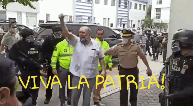 a man in a white shirt is being escorted by a group of police officers with the words viva la patria written in yellow
