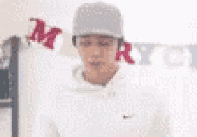 a man wearing a baseball cap is standing in front of a merry christmas banner .