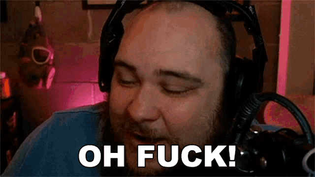 a man wearing headphones is sitting in front of a microphone and saying oh fuck !
