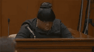 a woman is sitting at a podium with her head resting on her hand .