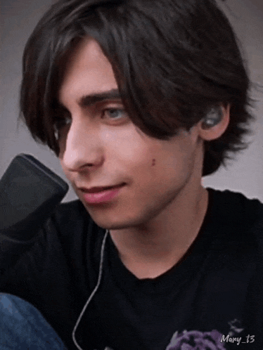 a close up of a young man wearing ear buds and a black shirt with mary 13 written on the bottom
