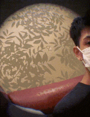 a man wearing a face mask looks at a red couch