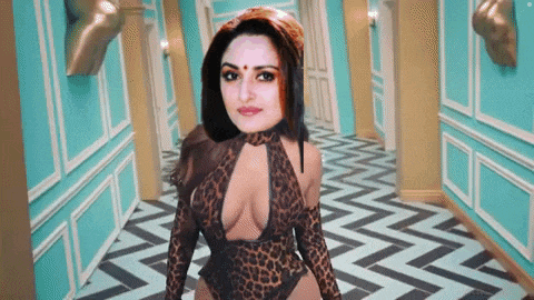 a woman in a leopard print bodysuit is standing in a hallway with a chevron floor .