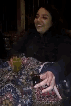 a woman sitting at a table holding a shot glass with the number 38 on it