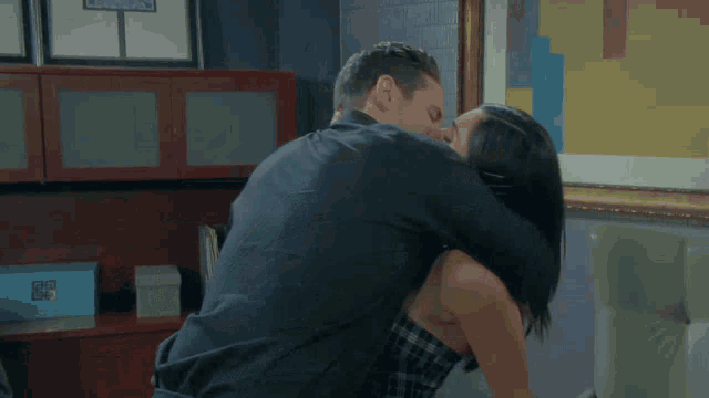 a man and a woman are kissing in front of a framed picture