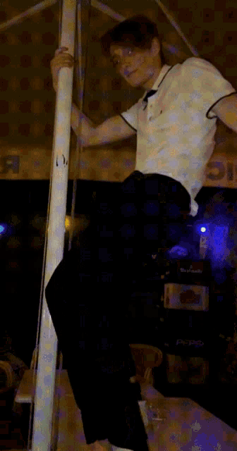 a man in a white shirt and black pants is standing on a pole and laughing
