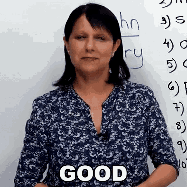 a woman is standing in front of a white board with the word good written on it