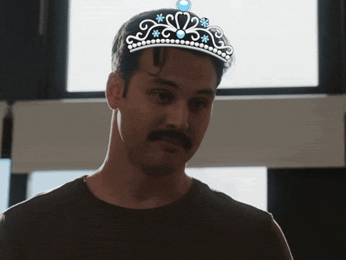 a man with a mustache is wearing a tiara