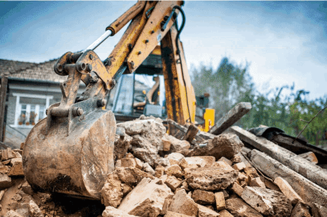 a yellow excavator scoops up a pile of rocks