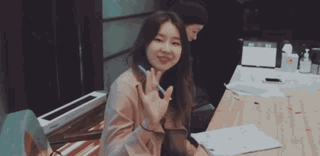 a woman is sitting at a table holding a pen