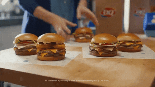 a bunch of hamburgers are sitting on a table with a sign that says " for a limited time at participating locations "
