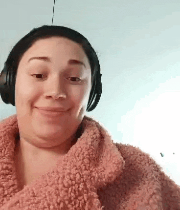 a woman wearing headphones and a pink sweater is smiling for the camera .