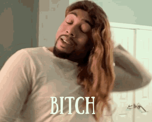 a man with long hair is wearing a white shirt with the word bitch on it
