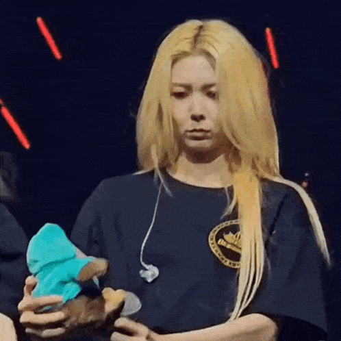 a woman in a black shirt is holding a stuffed animal in her hands .