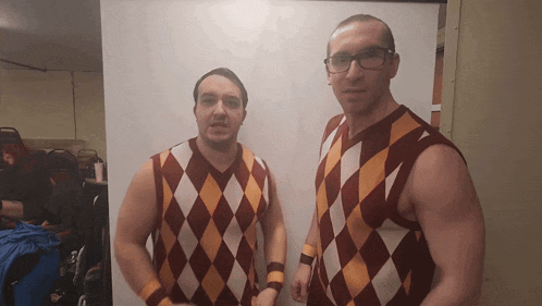 two men standing next to each other wearing argyle sweaters and wristbands