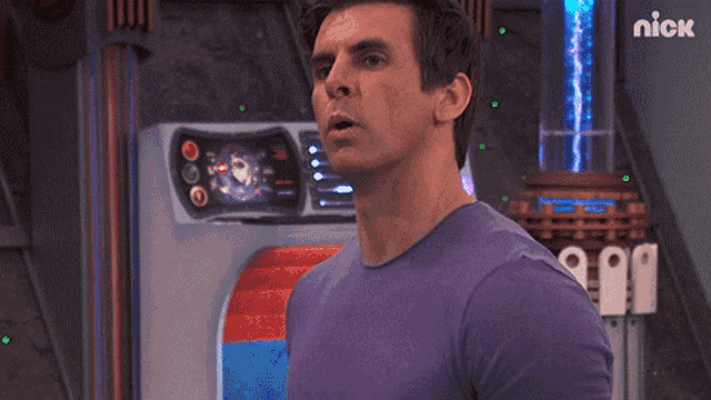 a man in a purple shirt is standing in front of a machine that says nick on it