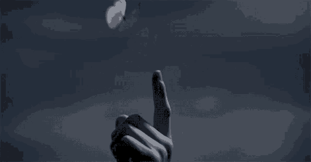 a person 's finger is pointing at a butterfly flying in the air