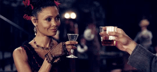 a woman is smoking a cigarette while a man holds a glass of whiskey in front of her .