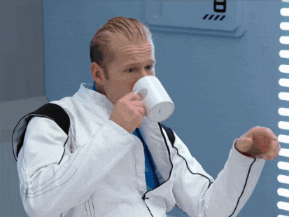 a man in a white jacket drinking from a white cup