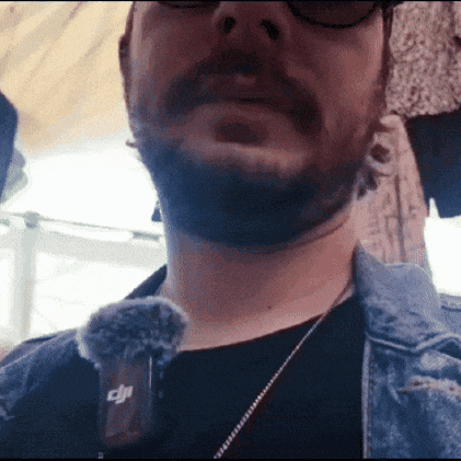 a man with a beard is wearing a dji microphone on his neck .