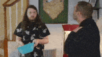 two men are standing next to each other and one of them is holding a piece of paper