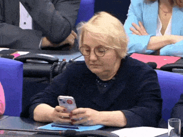 a woman sitting at a table using a cell phone with a sticker on it that says stop