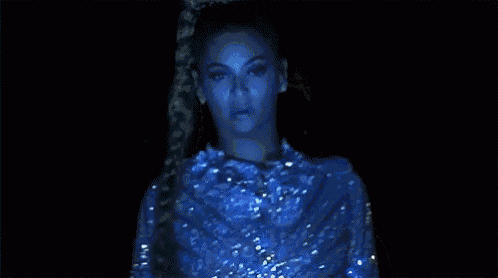 a woman with a braid in her hair is wearing a silver dress and earrings .