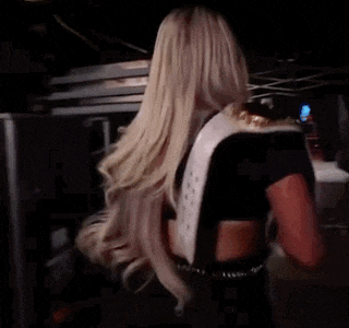a woman with long blonde hair is holding a wrestling belt around her waist .