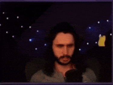 a man with a beard is sitting in front of a microphone