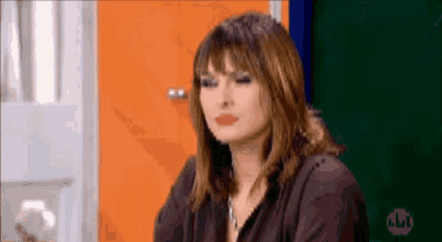 a woman with a serious look on her face is sitting in front of a door .