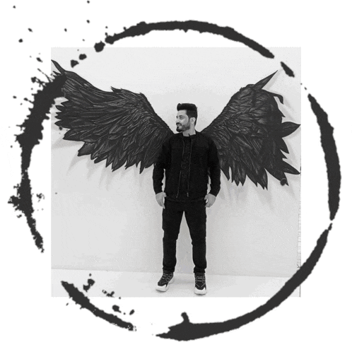 a man is standing in front of a painting of wings on the wall