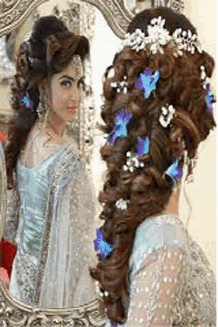 a woman is looking at herself in a mirror with flowers in her hair