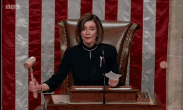 a woman is sitting in a chair holding a mallet in front of a flag .