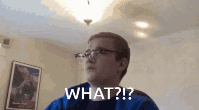 a man with glasses and a blue shirt says " what ? "