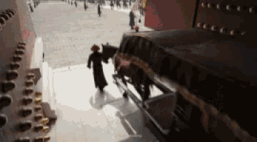a man is pushing a horse drawn carriage down stairs .