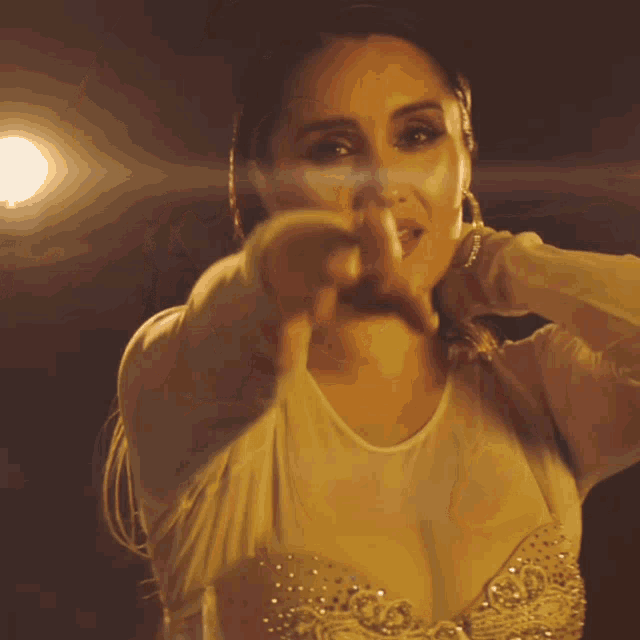 a woman in a white top is pointing her finger at the camera