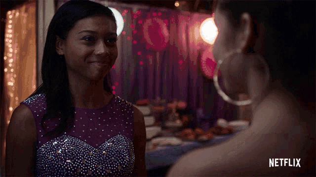 a woman in a purple dress is smiling next to another woman with netflix written in the corner