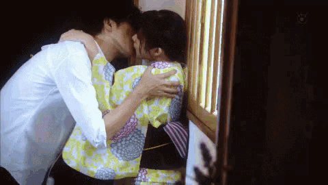 a man in a white shirt kisses a woman in a yellow kimono