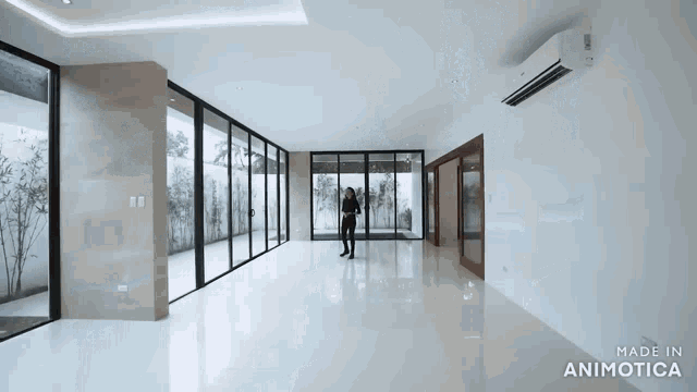 a woman is standing in a large empty room with a made in animatica logo